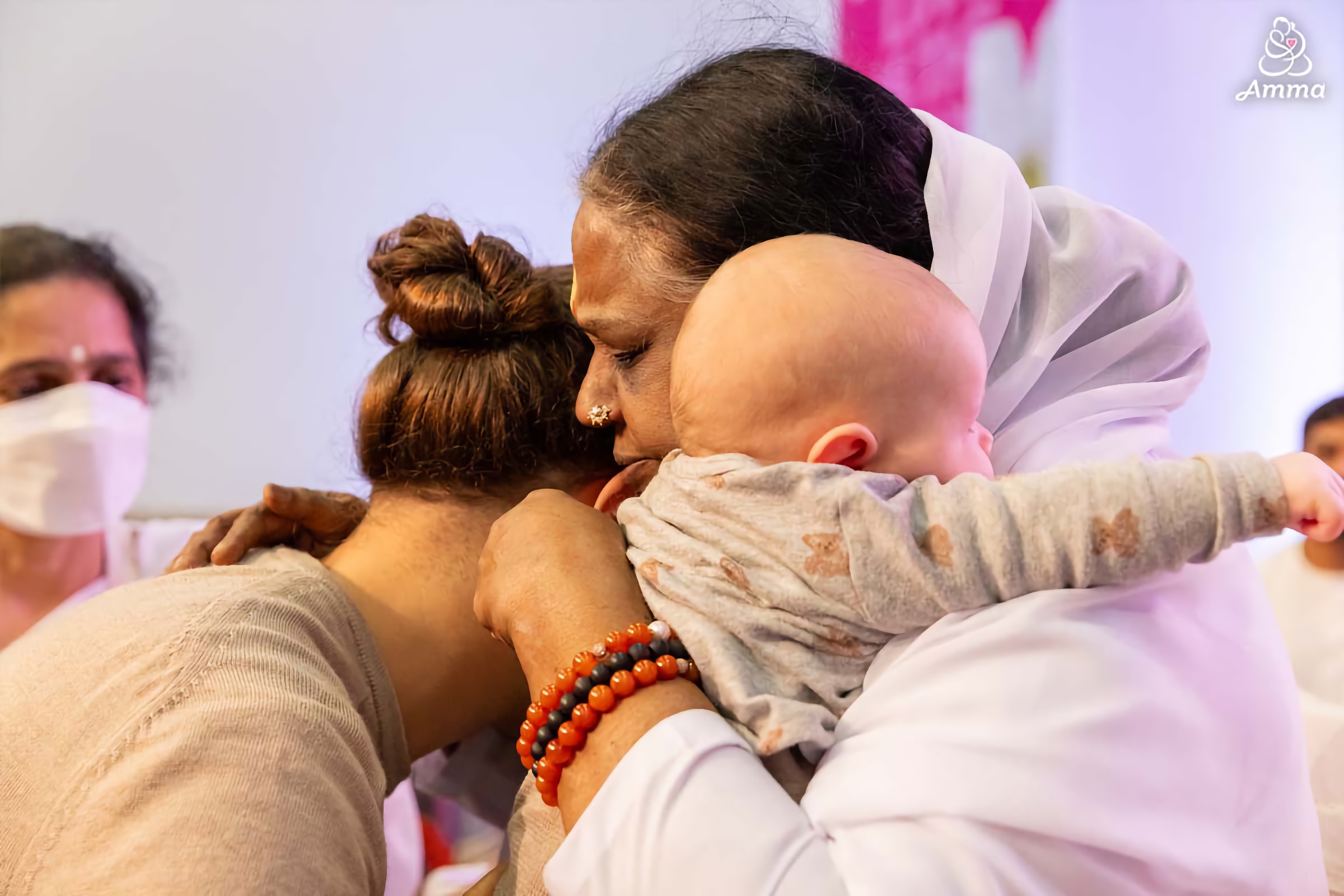 Amma embracing a mother and her baby