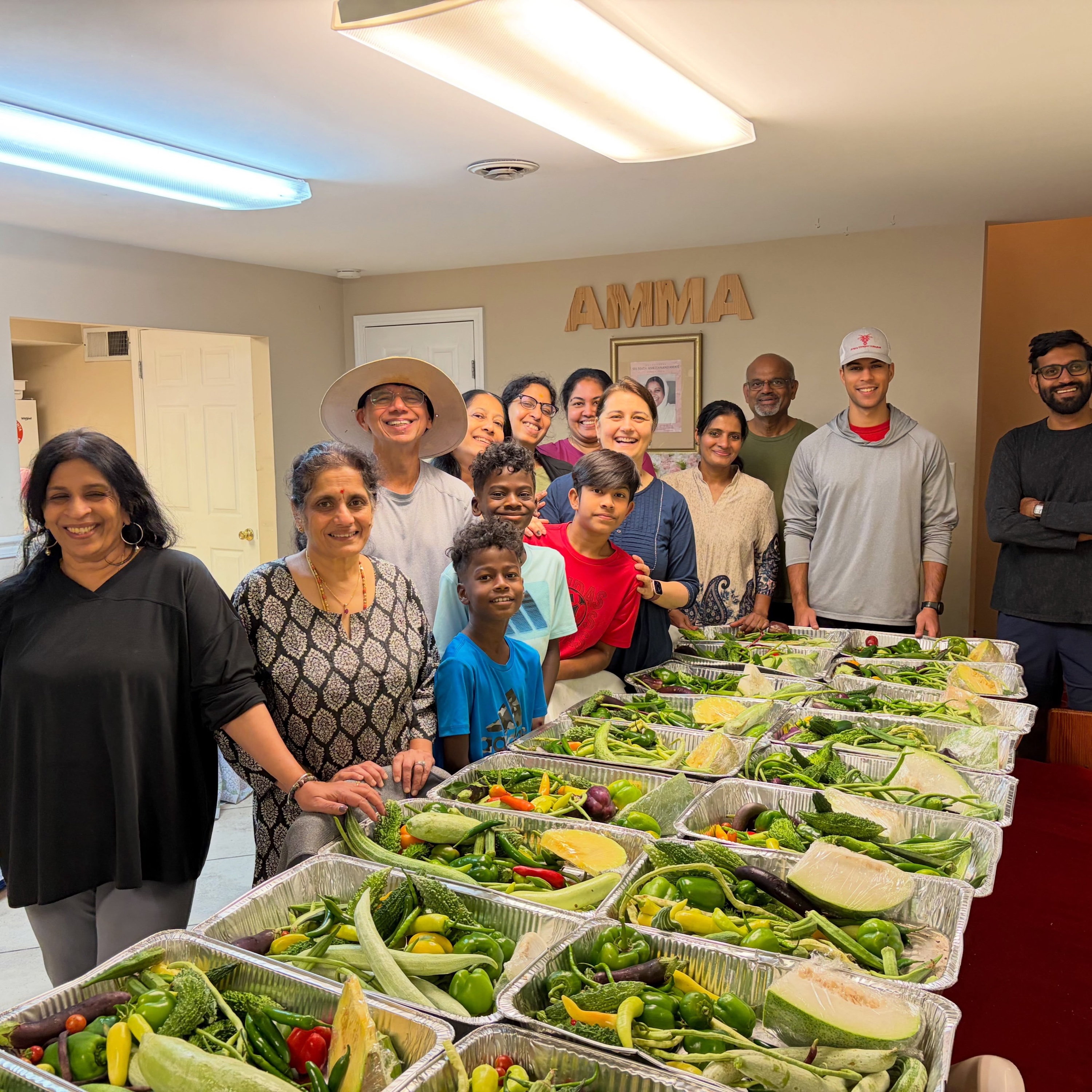 MA Center Atlanta satsang members behind trays of freshly packed garden vegetables