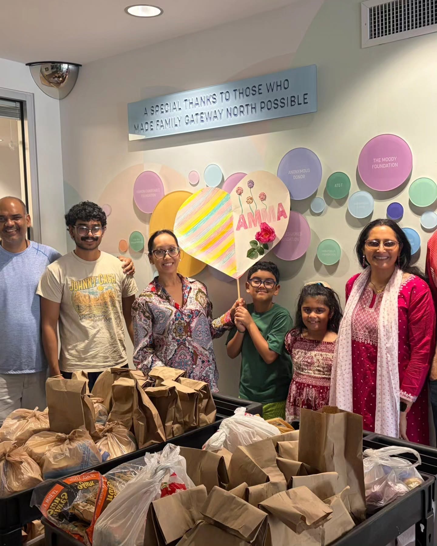 MA Center Dallas Mother’s Kitchen volunteers with lunch bags and a birthday sign for Amma