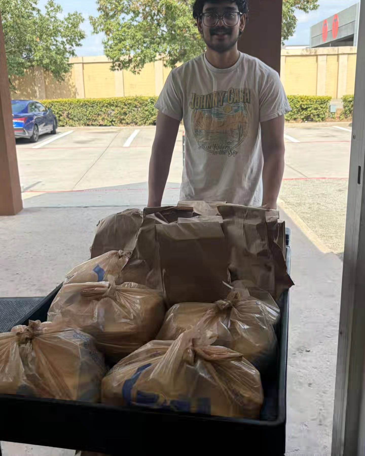 Volunteer with a cart of Mother’s Kitchen lunch bags ready for delivery