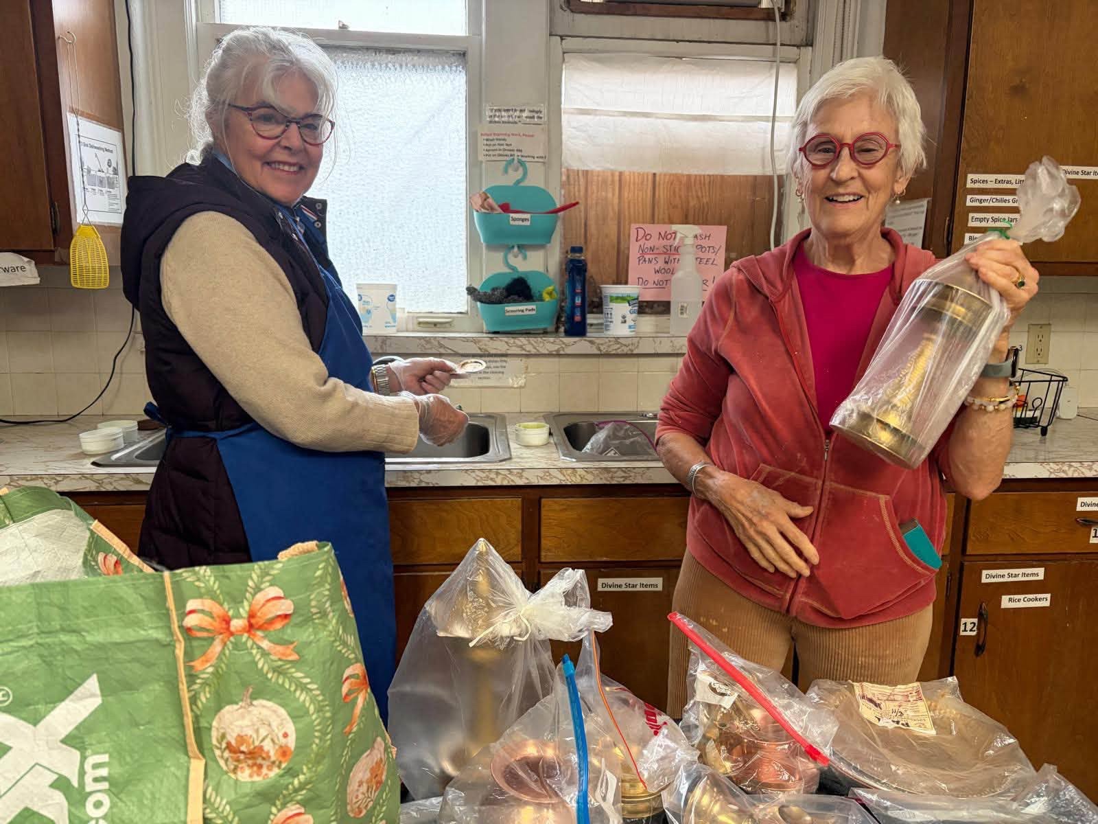 Two MA Center Iowa volunteers smiling while cleaning the ashram kitchen