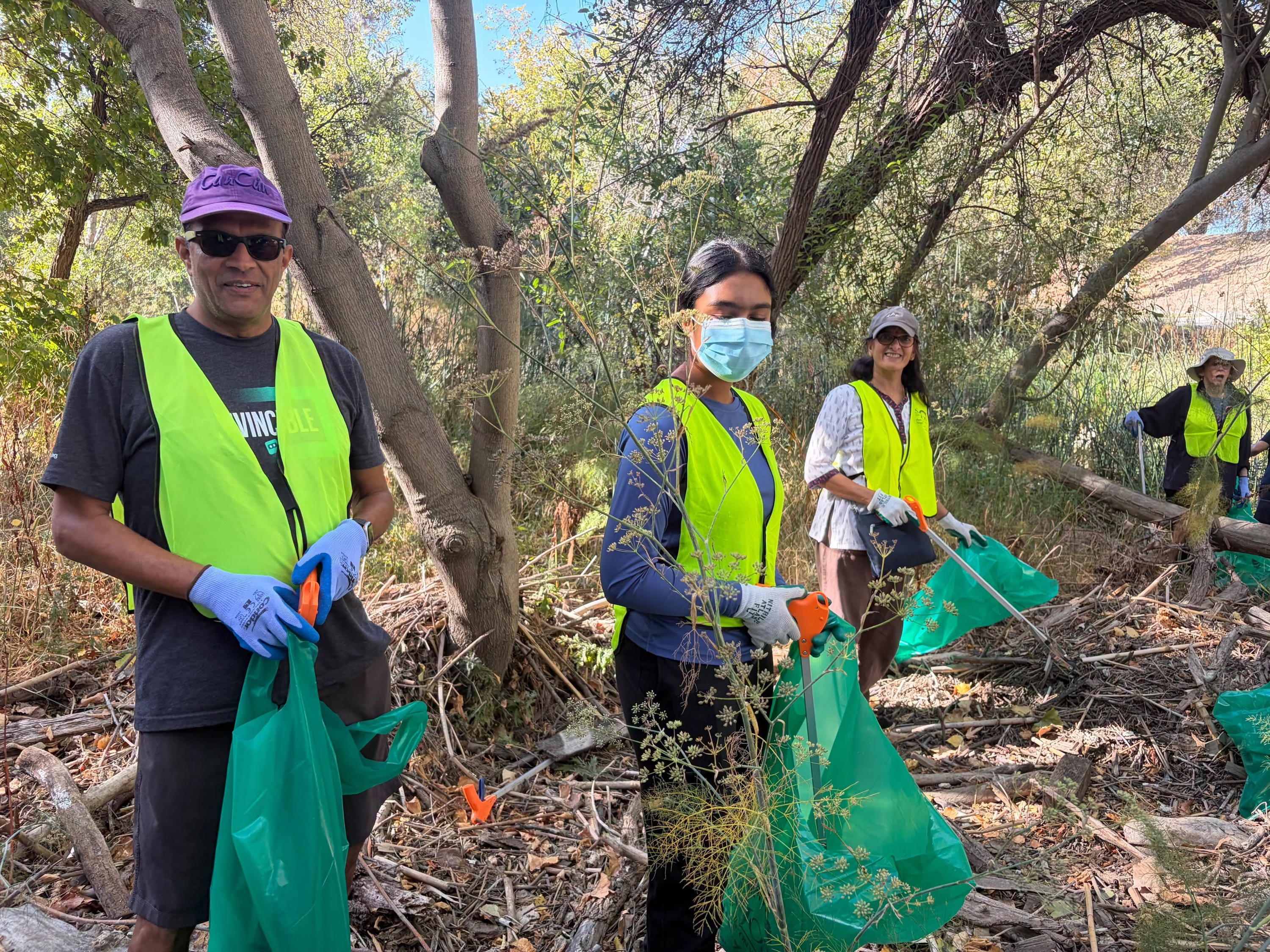 MA Center San Ramon volunteers in safety vests with trash bags along the Guadalupe River