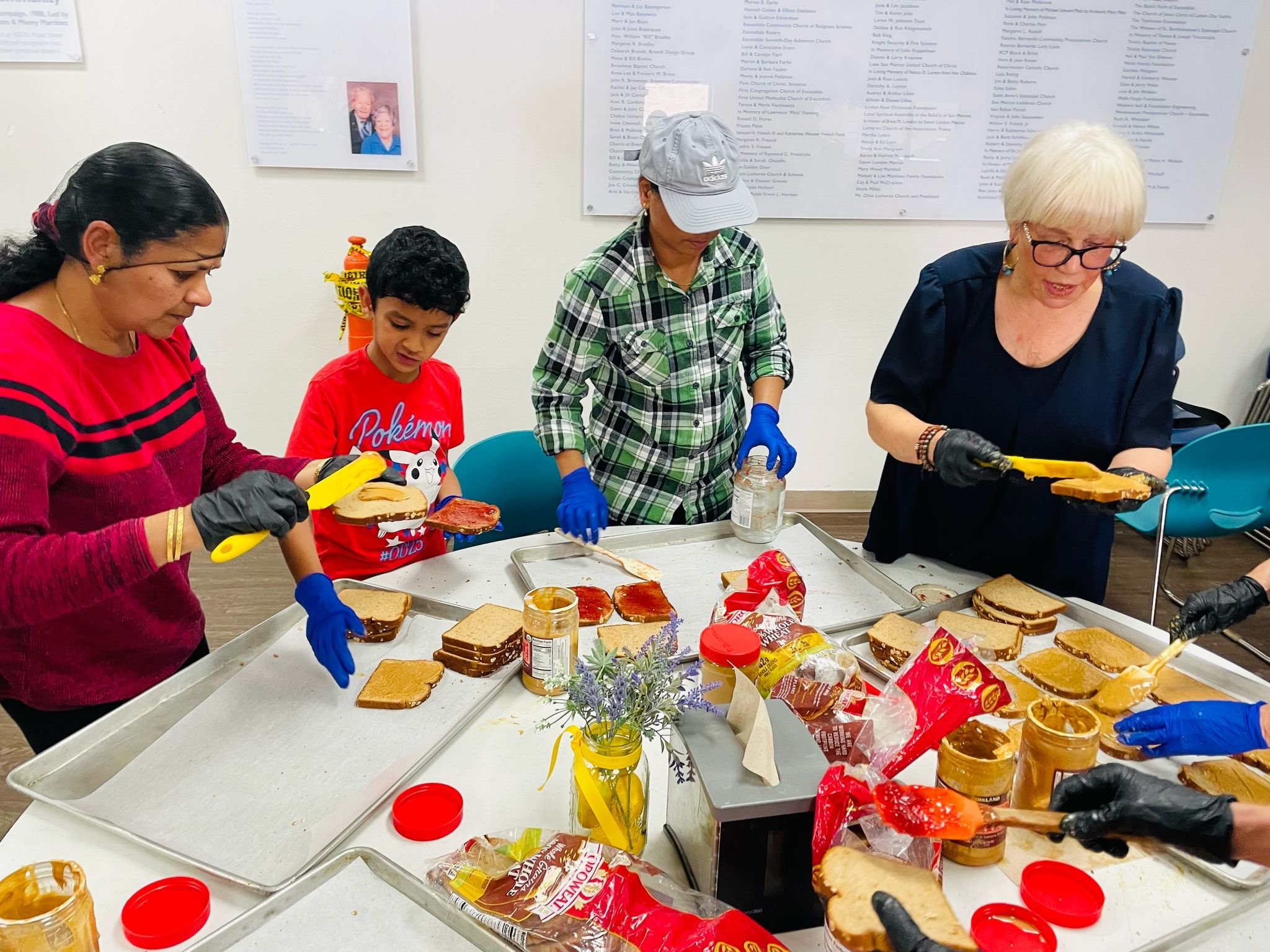Volunteers of all ages making peanut-butter-and-jelly sandwiches