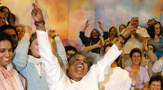 Amma Smiling and arms raised with crowd behind