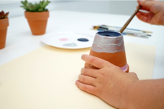 Hands painting a flower pot