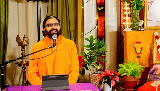 Br. Ramanandamrita Chaitanya speaking at a microphone