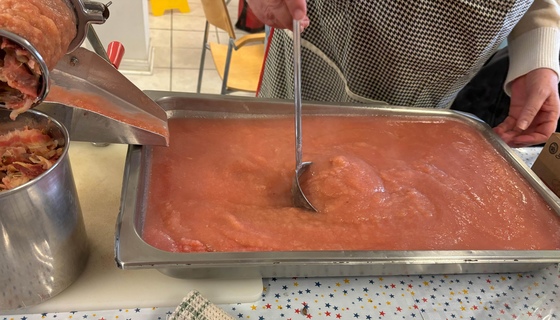 Pink applesauce being made with a food mill