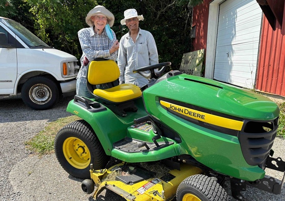 Amma Canada volunteers with John Deere riding lawnmower