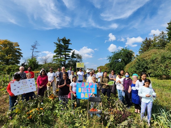 Farm volunteers holding signs saying 'Happy Birthday, Amma!'