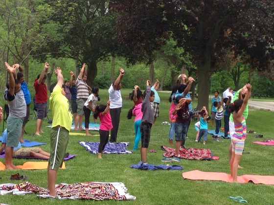Amrita Bala Kendra kids & their parents participating in Yoga Day Kids and adults doing yoga together outdoors