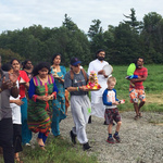 Group of adults and children in procession with Krishna murtis