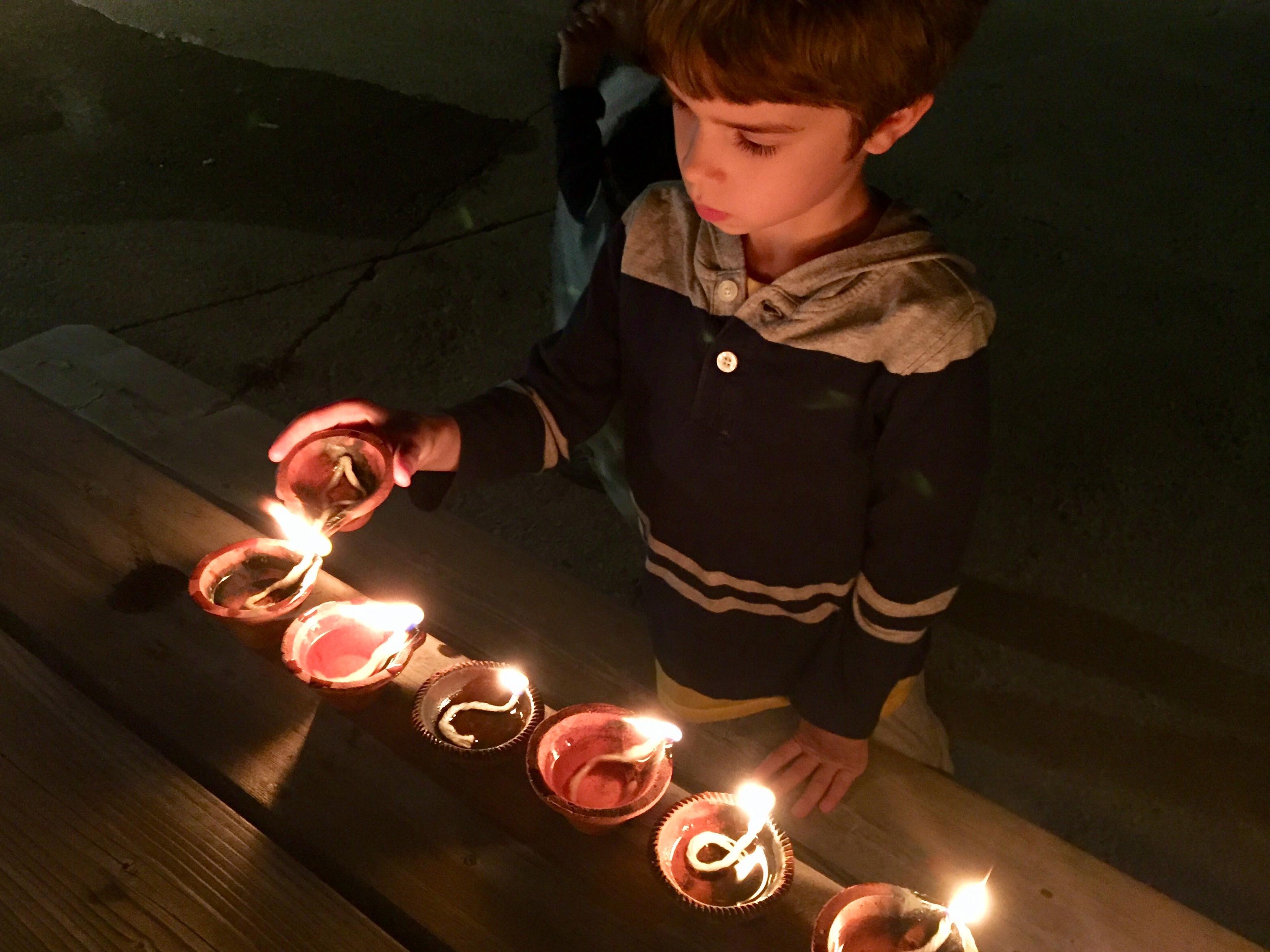 Boy lighting a small oil lamp