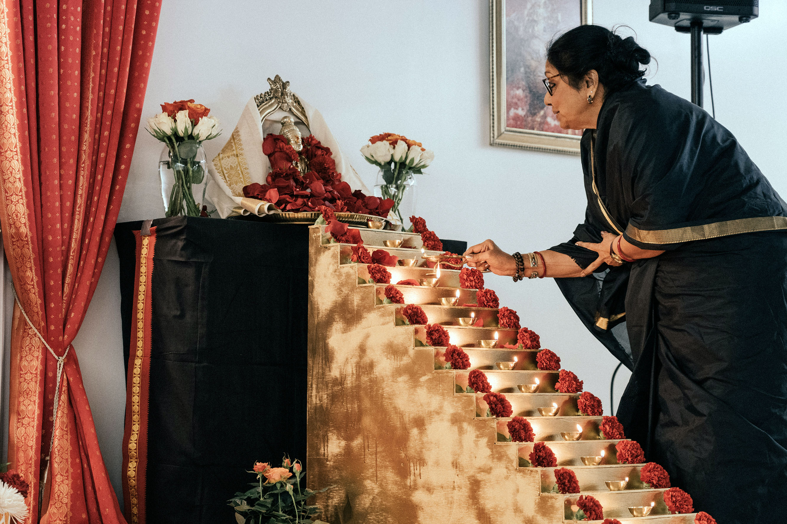 Woman lighting lamps on small steps leading to Ayyappa statue