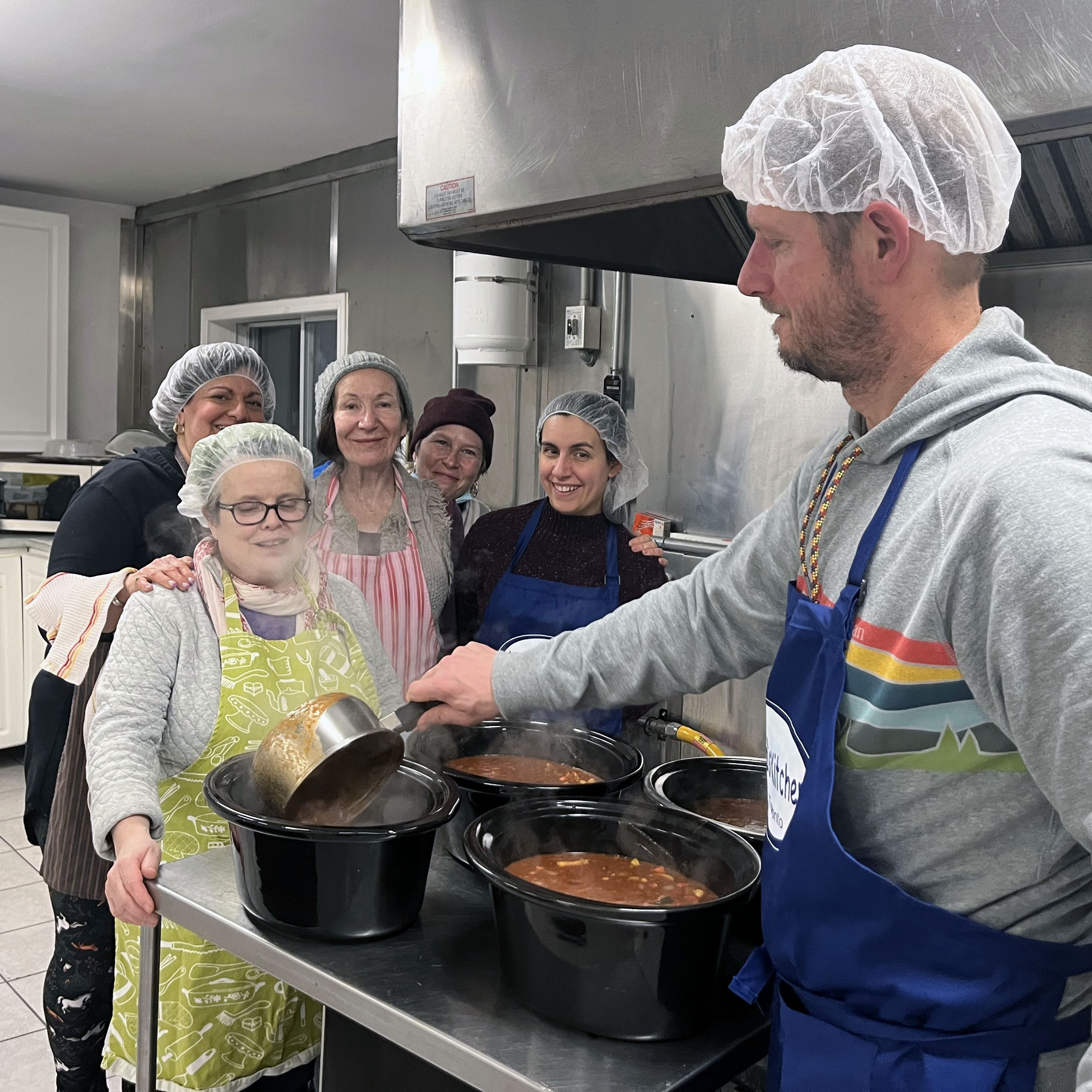 Volunteer group photo with prepared chilli being portioned into crock pots