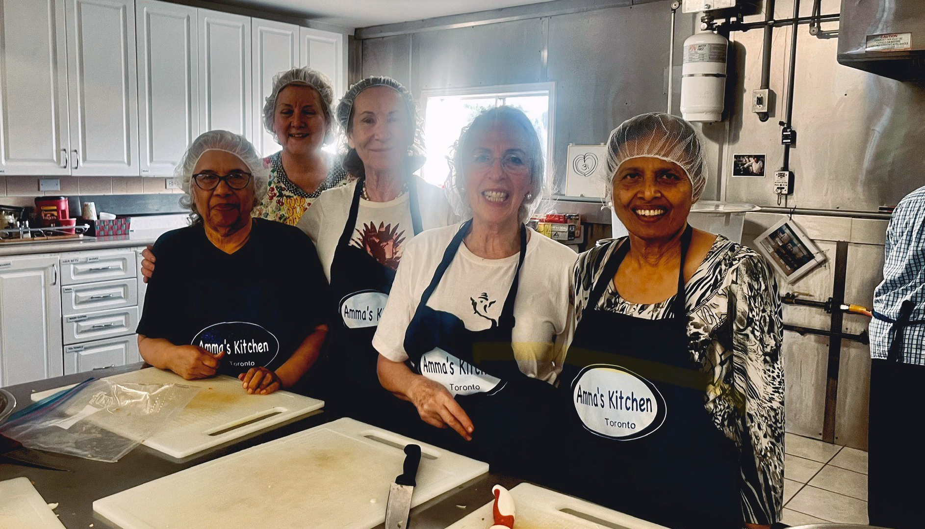 Volunteers ready to chop veggies in the Amma Canada kitchen