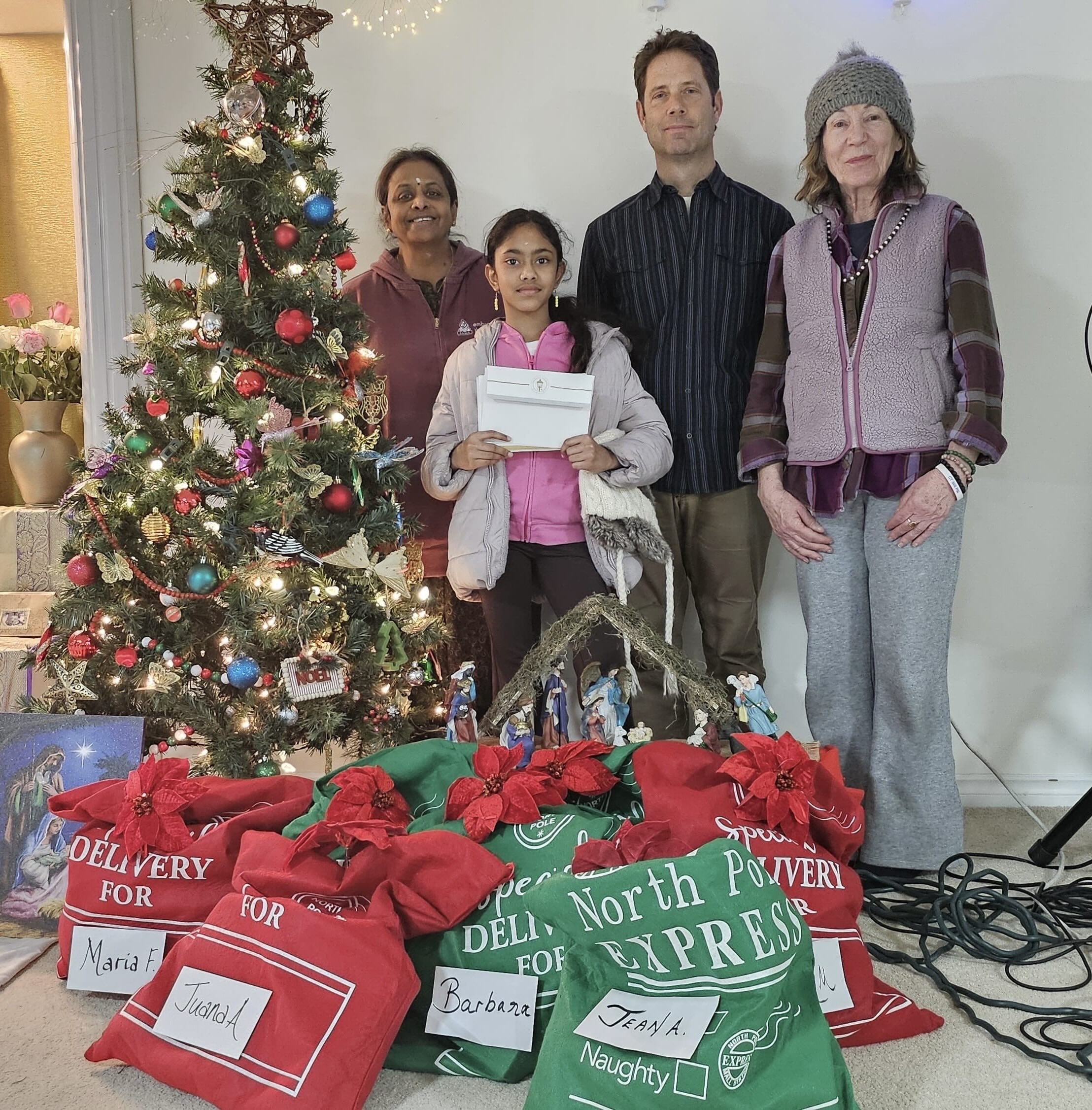 Volunteers with gifts in Santa sacs by Xmas tree