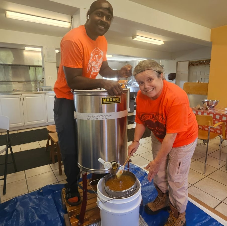 Two people extracting honey with manual extractor