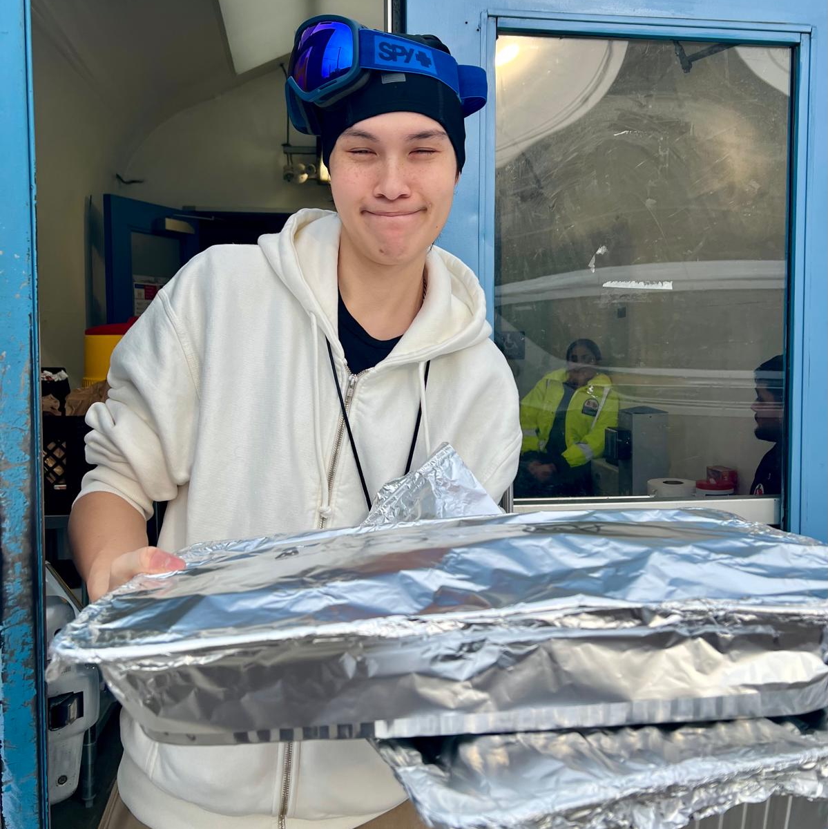 St. Felix staff member holding two trays of cookies from Amma Canada