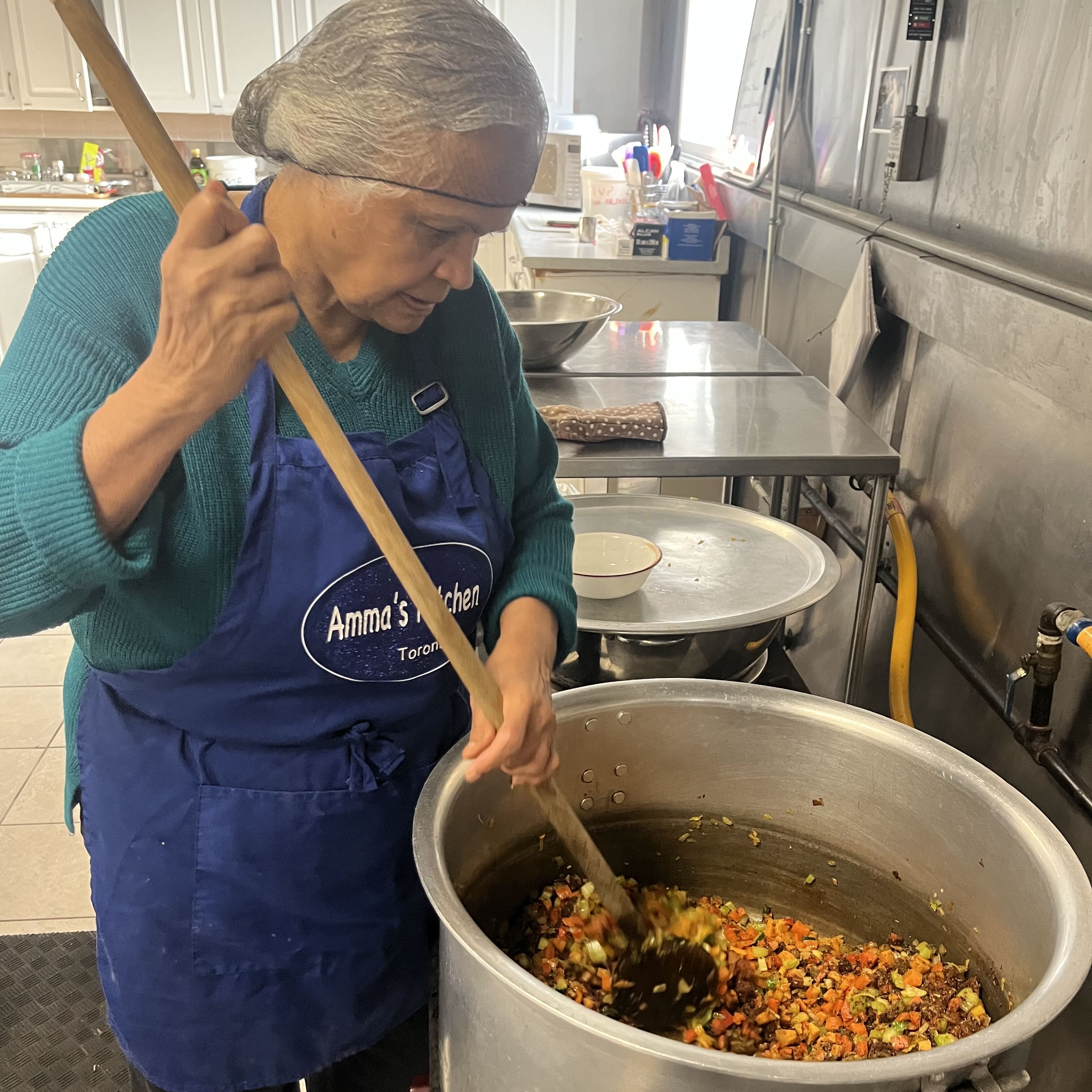 Amma Canada volunteer stirring chilli