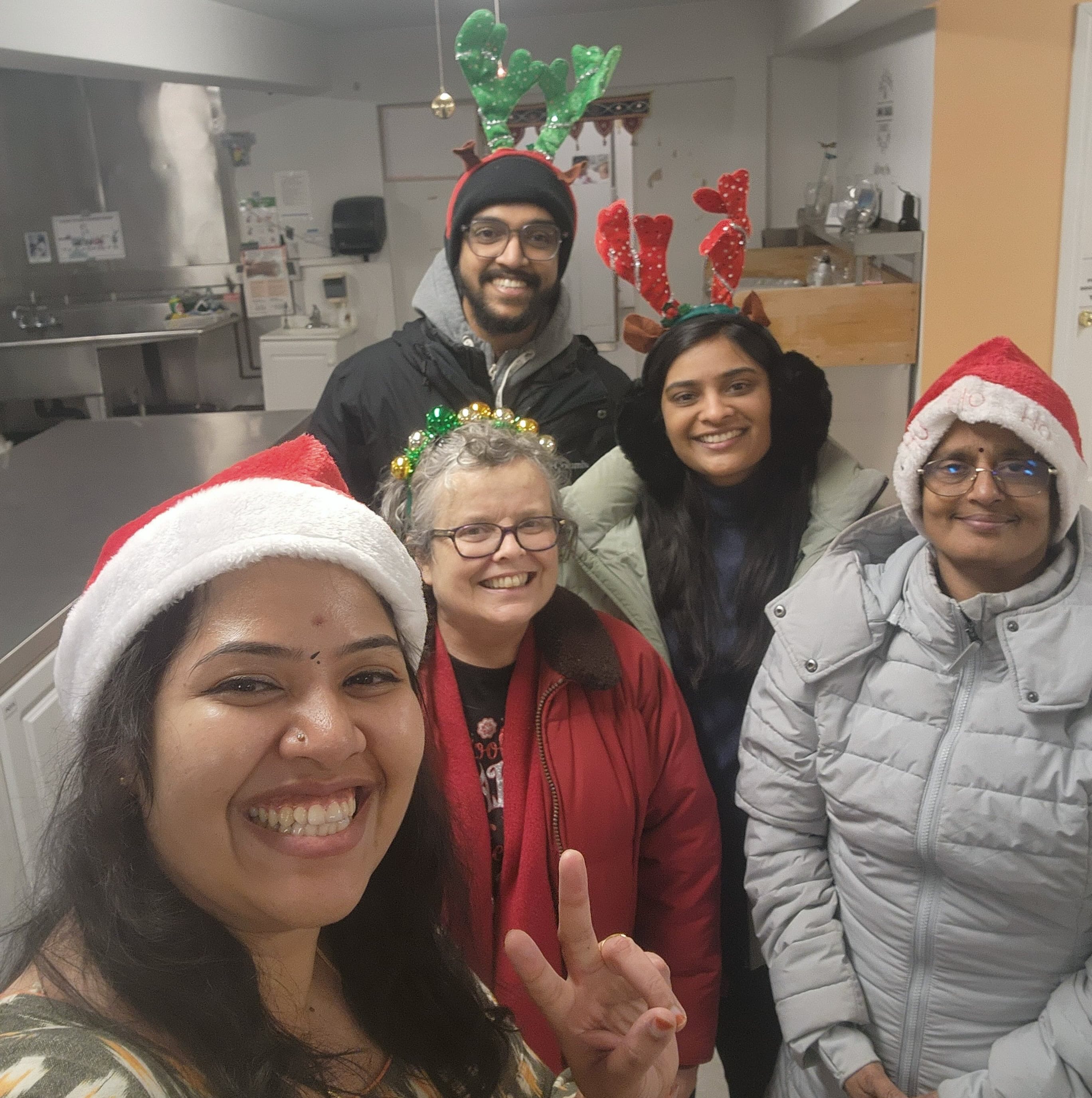 Volunteers with Santa hats and reindeer antlers in the Amma Canada kitchen