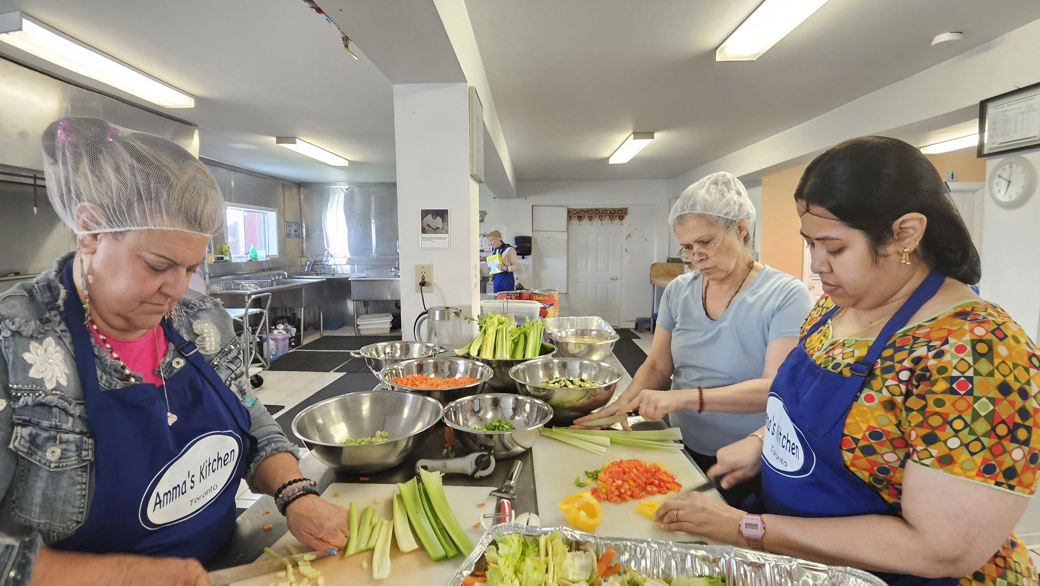 Volunteers ready to chop veggies in the Amma Canada kitchen