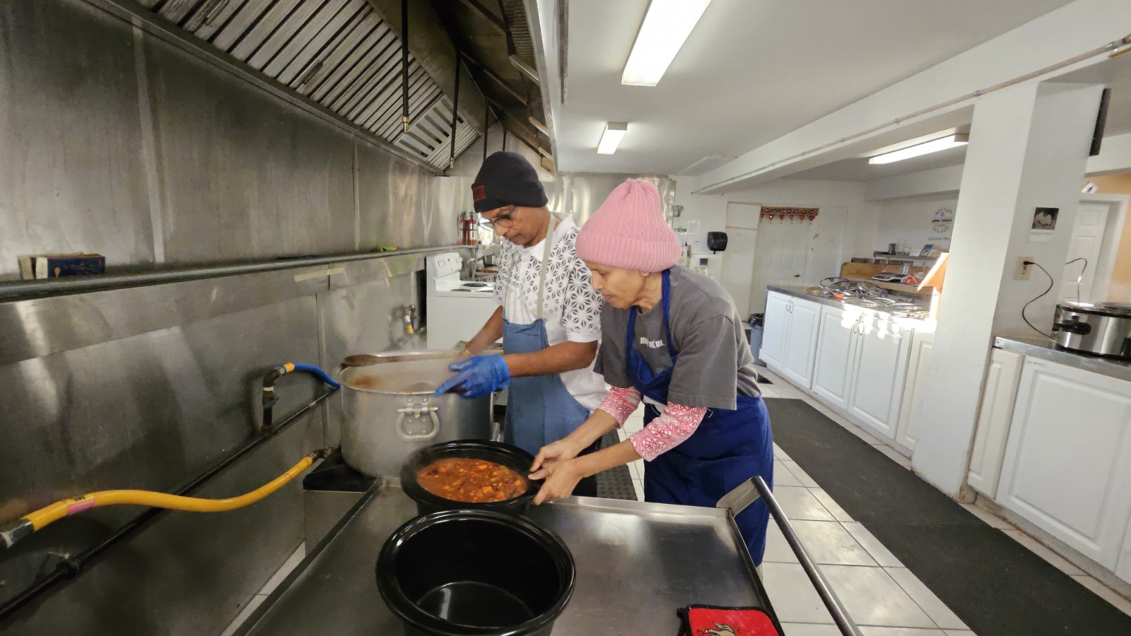 Lead cooks transferring chilli into crock pots